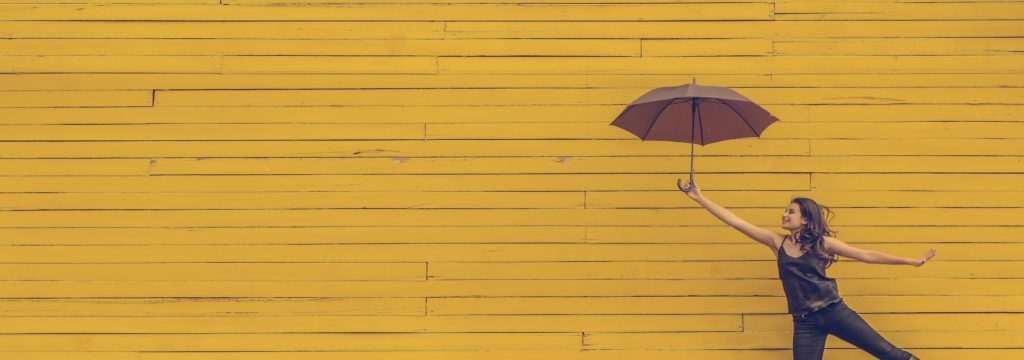 travel agency brand woman with umbrella yellow wall
